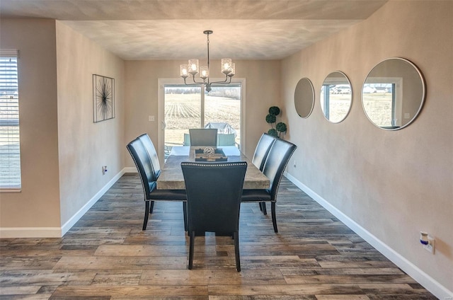 dining space with dark wood-style flooring, a healthy amount of sunlight, a notable chandelier, and baseboards