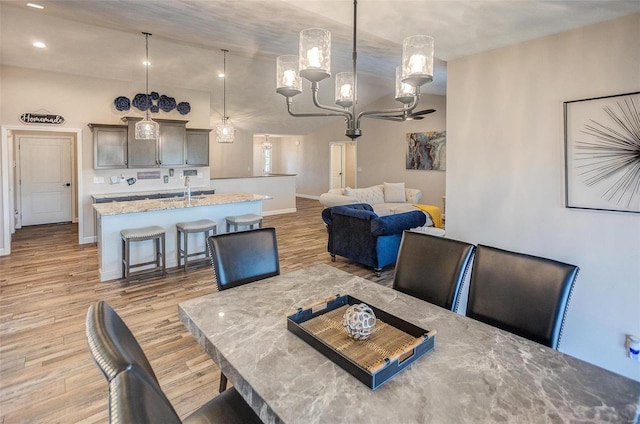 dining area featuring baseboards, vaulted ceiling, and light wood finished floors