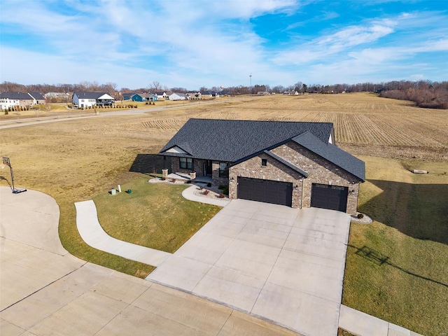 view of front of home with a rural view, a garage, driveway, roof with shingles, and a front lawn