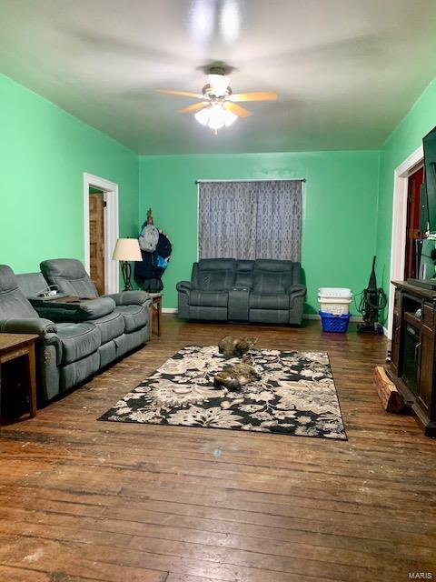 living area with a ceiling fan, dark wood finished floors, and baseboards