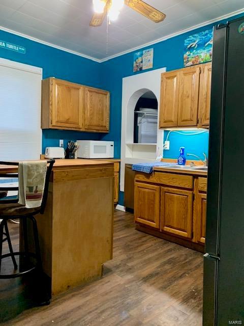 kitchen with white microwave, brown cabinets, dark wood-style flooring, light countertops, and a sink