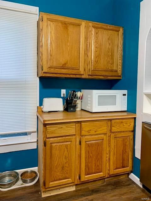 kitchen featuring dark wood-style floors, brown cabinets, light countertops, and white microwave