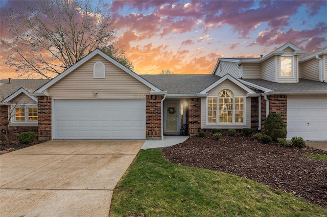 traditional home featuring brick siding, concrete driveway, a garage, and roof with shingles