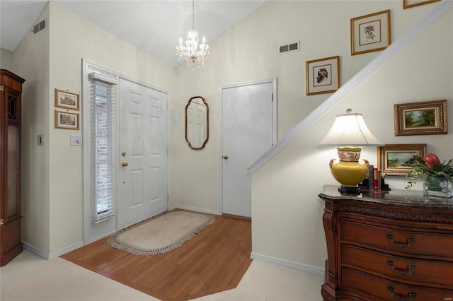 foyer entrance featuring wood finished floors, visible vents, a chandelier, and baseboards