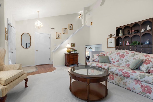 living area featuring stairway, visible vents, carpet floors, high vaulted ceiling, and a chandelier