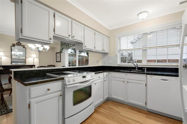 kitchen featuring crown molding, a peninsula, white appliances, white cabinetry, and a sink