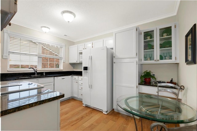 kitchen featuring light wood-style flooring, a sink, dark countertops, white appliances, and glass insert cabinets