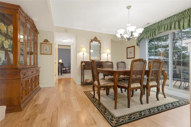 dining space featuring light wood-type flooring, baseboards, and a notable chandelier