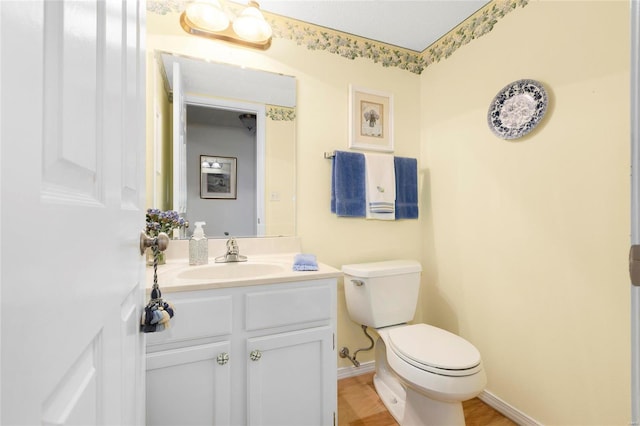 half bath with toilet, vanity, and baseboards