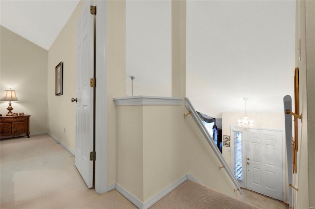 interior space featuring an inviting chandelier, lofted ceiling, carpet, and baseboards