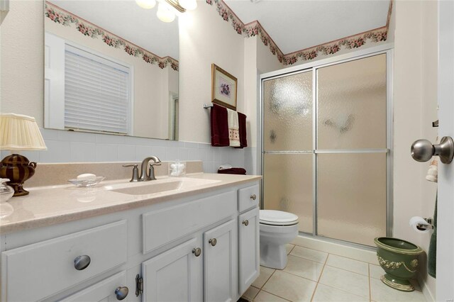 bathroom featuring vanity, a stall shower, tile patterned flooring, tile walls, and toilet