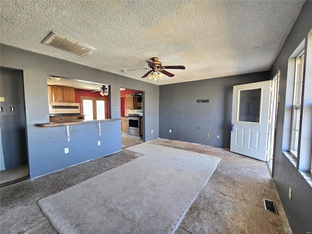 unfurnished living room with ceiling fan, visible vents, and a textured ceiling