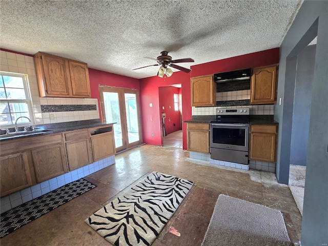 kitchen with brown cabinets, stainless steel range with electric cooktop, a sink, and tasteful backsplash