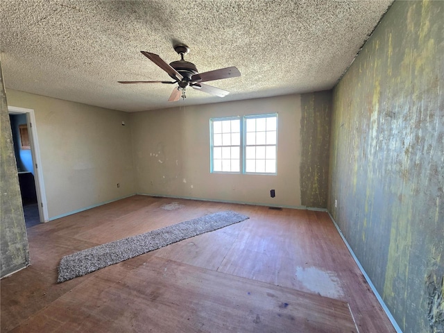 unfurnished room featuring visible vents, ceiling fan, a textured ceiling, and wood finished floors