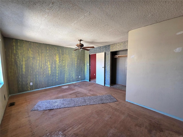 unfurnished bedroom featuring multiple closets, visible vents, ceiling fan, a textured ceiling, and baseboards