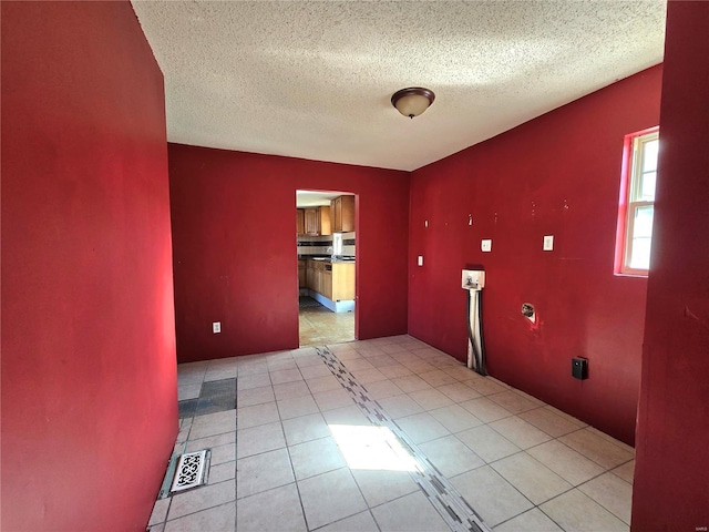 laundry area with laundry area, light tile patterned floors, visible vents, a textured ceiling, and washer hookup