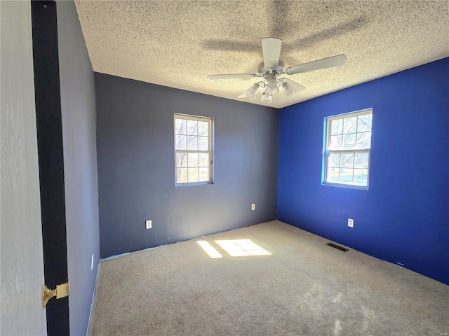 spare room featuring a healthy amount of sunlight, visible vents, and a textured ceiling