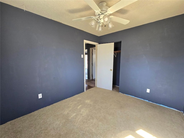 unfurnished bedroom featuring a textured ceiling, carpet floors, a closet, and a ceiling fan