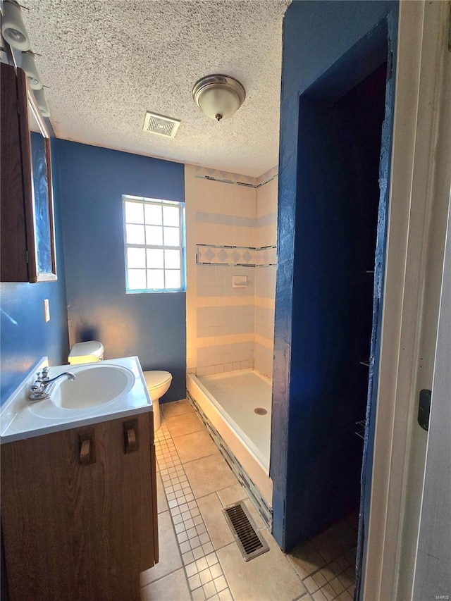 bathroom with toilet, a textured ceiling, tile patterned flooring, and visible vents