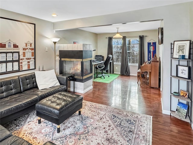 living room with a tile fireplace, wood finished floors, and baseboards