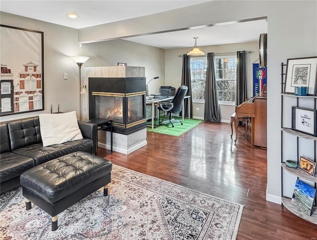 living area with baseboards, a tiled fireplace, and wood finished floors