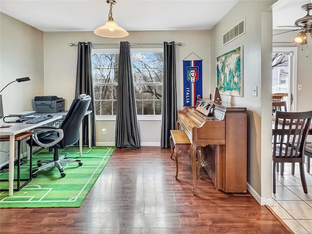 home office featuring a healthy amount of sunlight, ceiling fan, visible vents, and wood finished floors