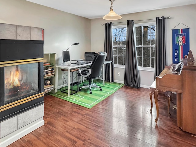 office space with a tiled fireplace, wood finished floors, and baseboards