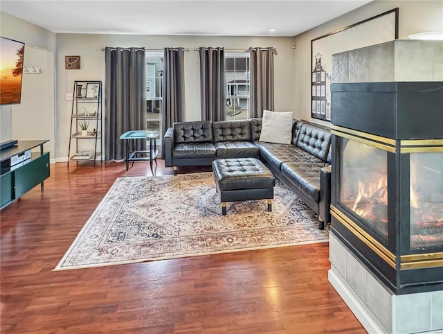 living area with baseboards, wood finished floors, and a multi sided fireplace