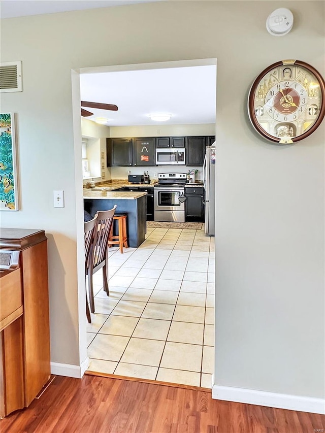 kitchen with visible vents, appliances with stainless steel finishes, light wood-style floors, a ceiling fan, and a peninsula