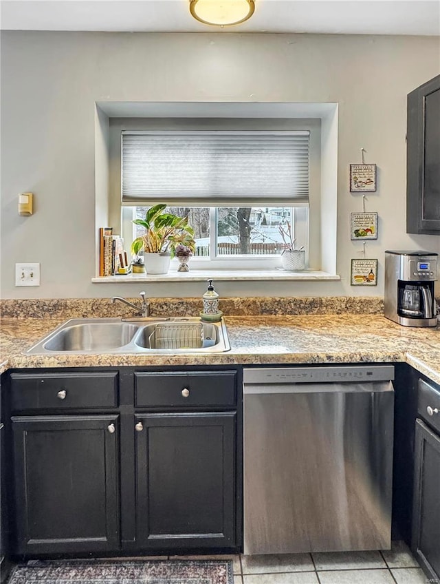 kitchen featuring light tile patterned floors, stainless steel dishwasher, a sink, and a healthy amount of sunlight