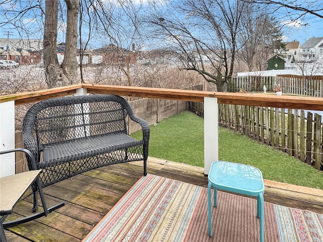 wooden terrace featuring a fenced backyard and a lawn