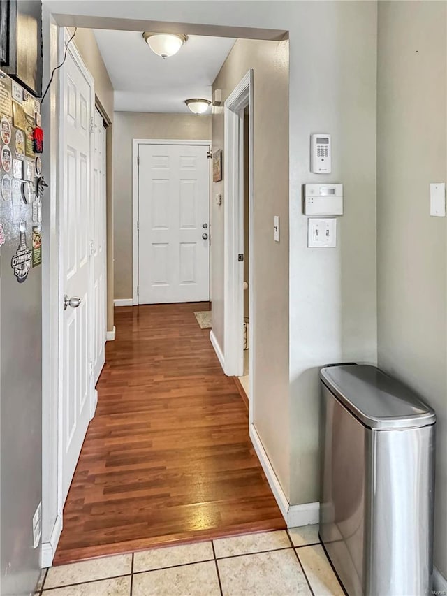 corridor with light tile patterned floors and baseboards