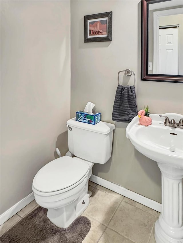 bathroom with toilet, baseboards, and tile patterned floors