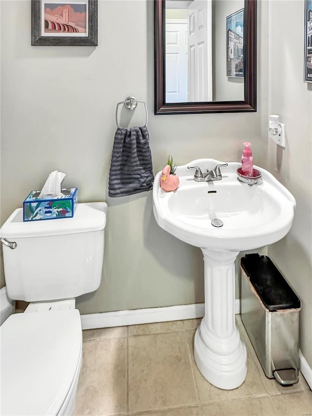 half bath with tile patterned flooring, baseboards, and toilet