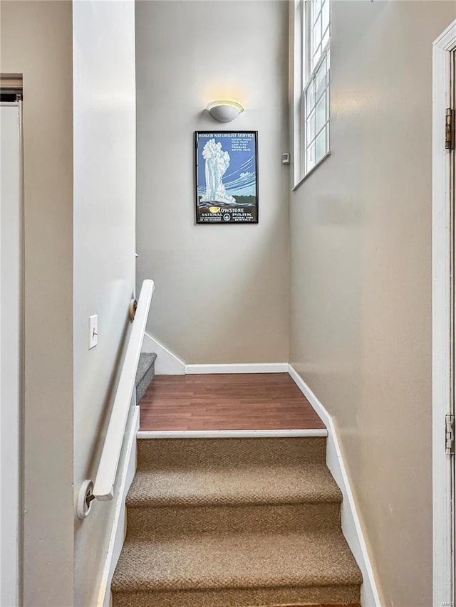 staircase featuring baseboards and wood finished floors