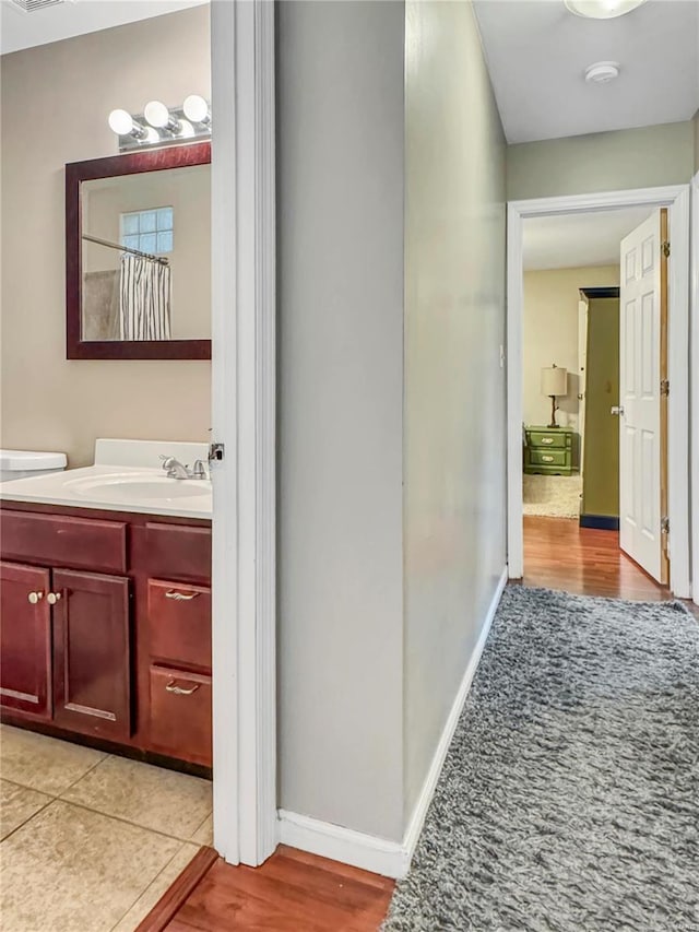 interior space featuring light wood finished floors, a sink, visible vents, and baseboards