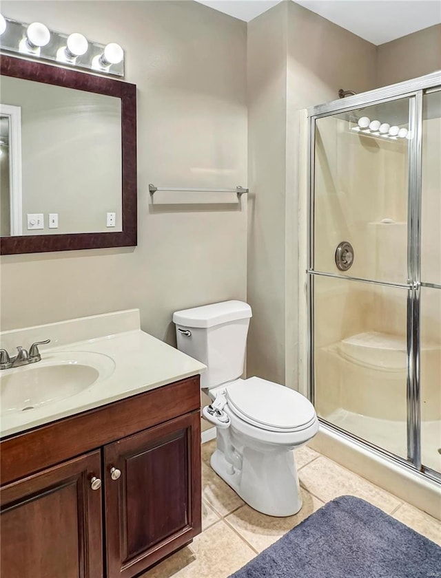 bathroom featuring toilet, a stall shower, vanity, and tile patterned floors