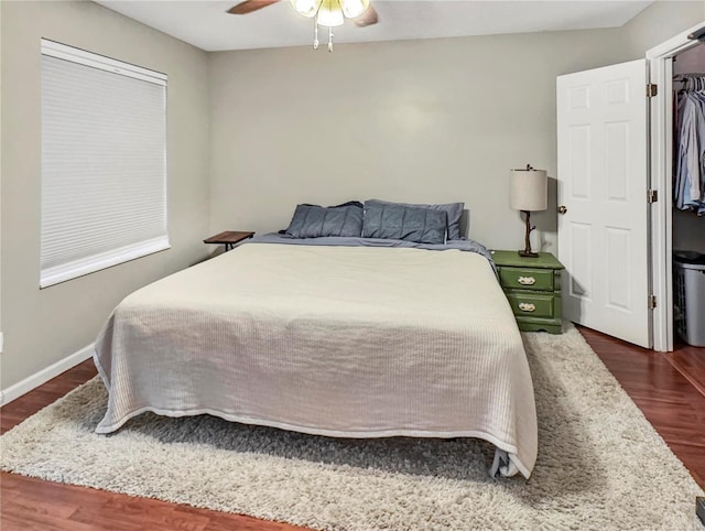 bedroom with dark wood-type flooring, a ceiling fan, and baseboards