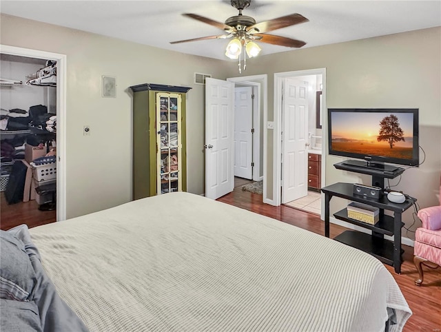 bedroom featuring visible vents, wood finished floors, ensuite bathroom, a walk in closet, and a closet