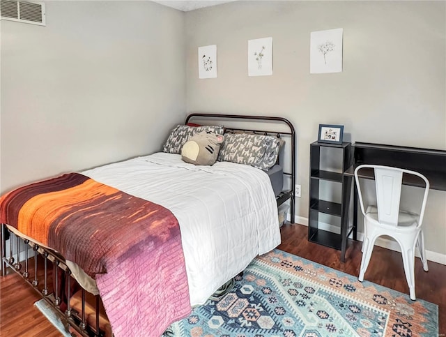 bedroom featuring wood finished floors, visible vents, and baseboards