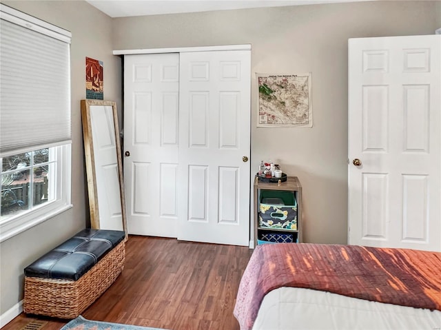 bedroom with a closet, dark wood-style flooring, and baseboards