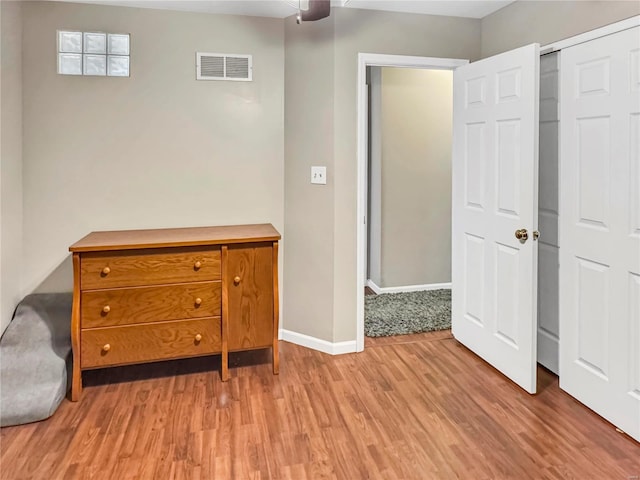 unfurnished bedroom featuring a ceiling fan, wood finished floors, visible vents, and baseboards