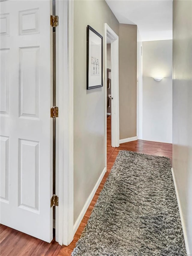 hallway featuring baseboards and wood finished floors