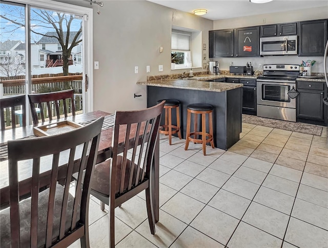 kitchen featuring a peninsula, a kitchen breakfast bar, stainless steel appliances, and light tile patterned flooring