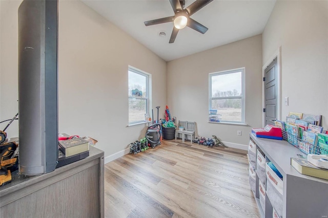 rec room featuring light wood-style floors, baseboards, and a ceiling fan