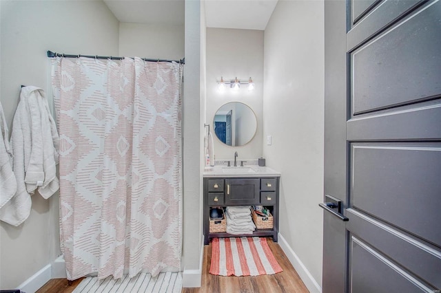 bathroom featuring curtained shower, vanity, baseboards, and wood finished floors