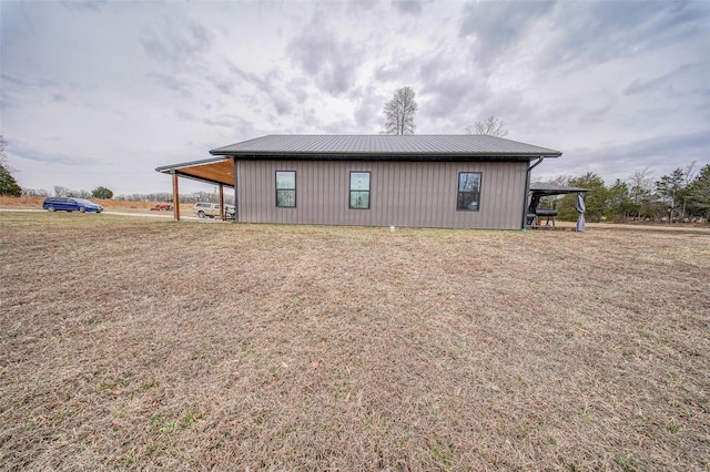 view of side of home featuring metal roof, a carport, and a lawn