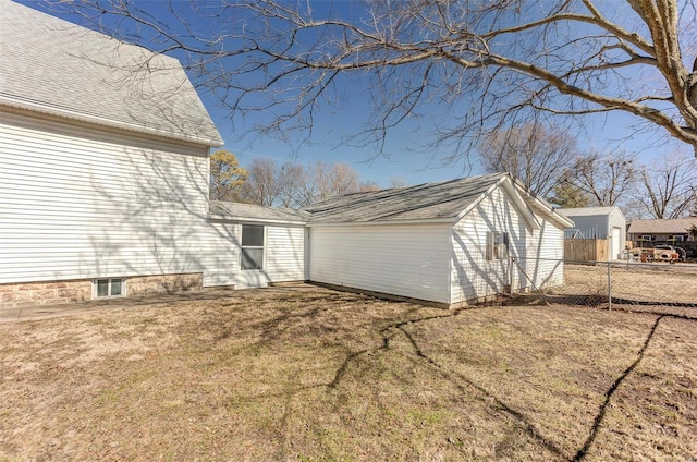 view of side of property featuring roof with shingles, fence, and a yard