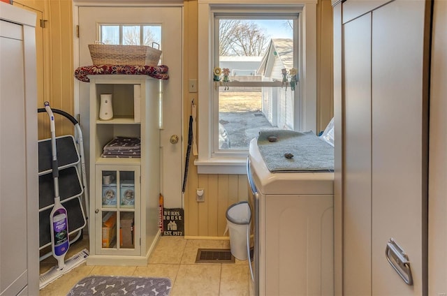 doorway to outside with washer / dryer, tile patterned flooring, visible vents, and wood walls