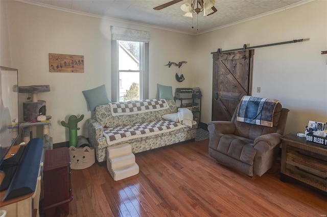 living room with a barn door, wood finished floors, a ceiling fan, and crown molding